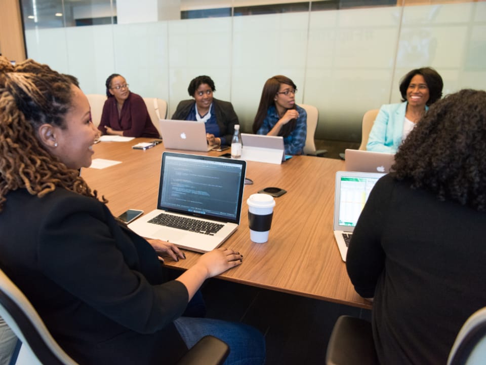 A small team working together around a conference table with laptops open