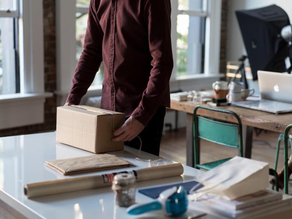 A retail worker packing an online order at the counter