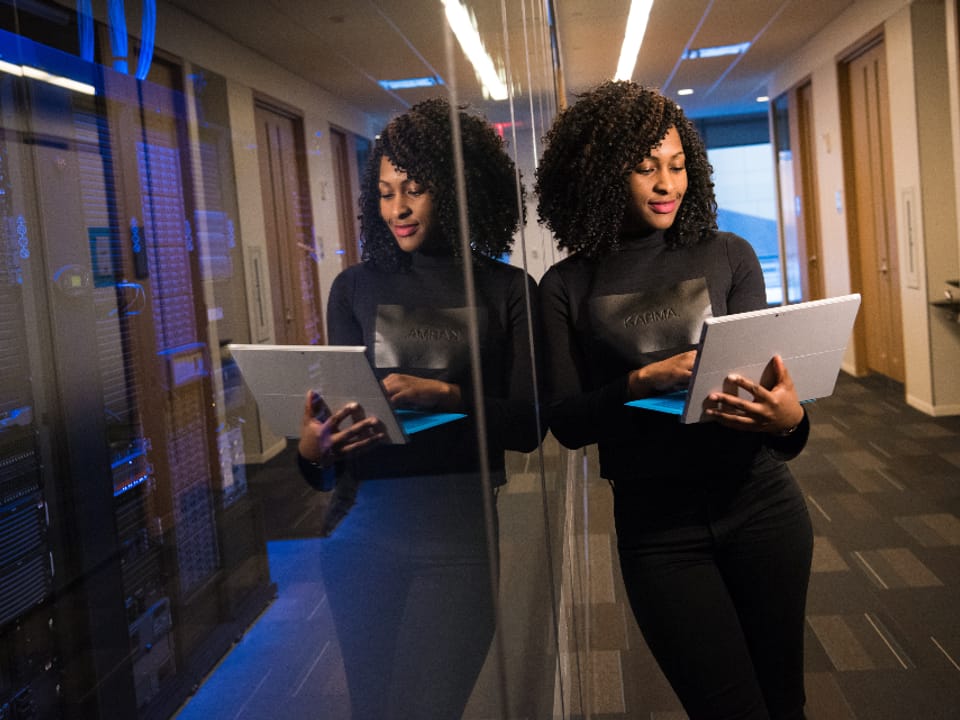An engineer checking a tablet in a glass-walled server room